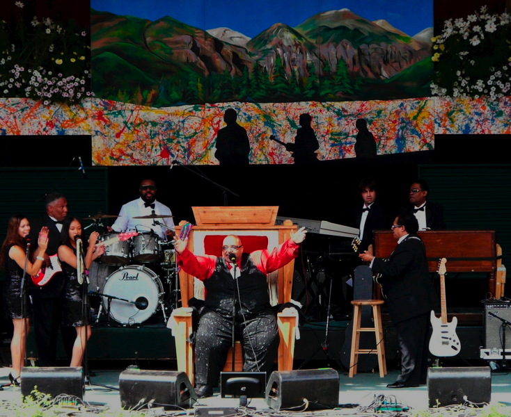 Solomon Burke performing while seated on the throne, flanked by his band.